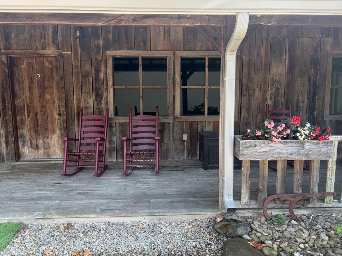 Covered porch with red rocking chairs and a flower box, outside an apartment door