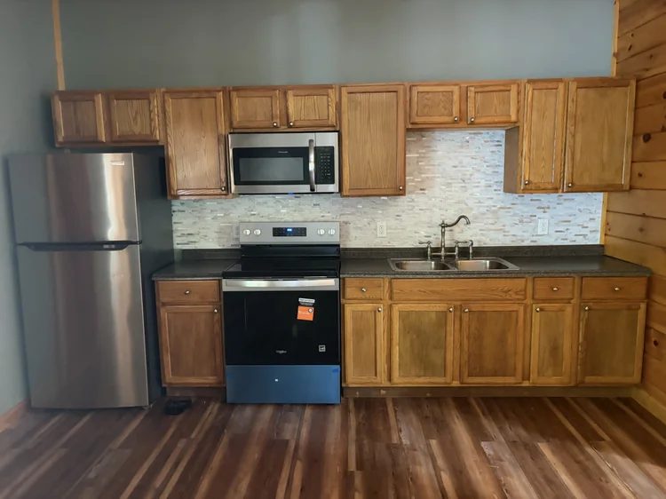 Kitchen with oak cabinets, a stainless refrigerator, stove and microwave, and a tile backsplash