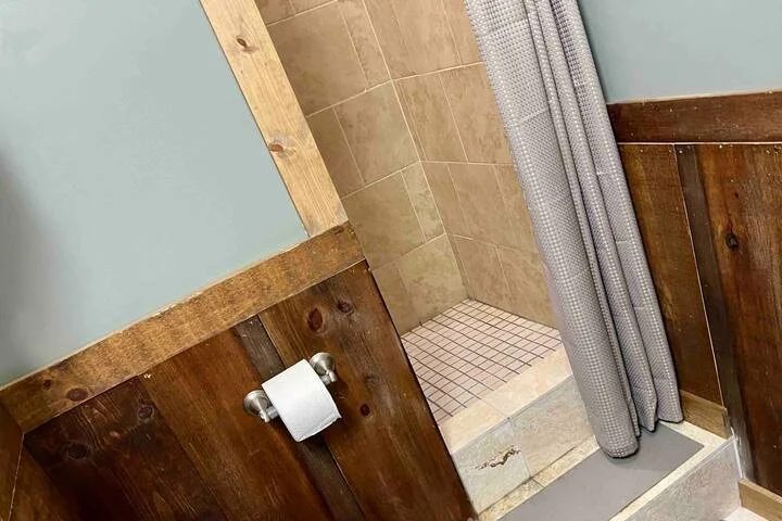 Walk-in tiled shower with a curtain and barn-wood trim