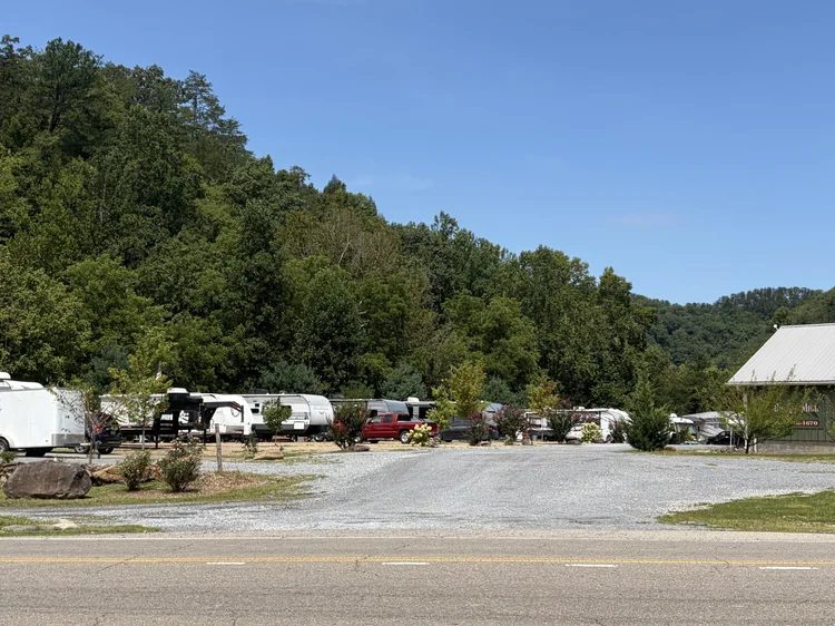 The gravel entrance to Dunn's Mill from the road, with RVs along the tree line